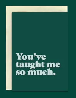 Close-up product image of a greeting card in front of a cream envelope. The card is a dark green. Bold, light green text at the bottom reads, 