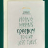 Close-up of a white greeting card on top of a cream-colored envelope, all on a forest green background. Card shows a hand drawn cake and hand lettering that reads "aging means freedom to give less fucks"