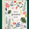 close up of the front of a greeting card, placed on top of a cream envelope and lying on top of a forest green background. Card features colorful floral and leaf graphics, with space in the center of the card for text. Text reads, "best grandma ever"