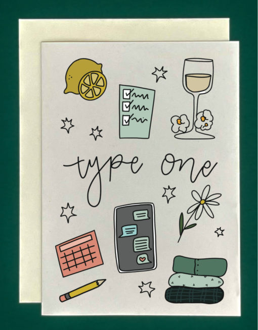 Close up of a white greeting card on top of a cream-colored envelope, all on a forest background. The card features “Type 1" written with drawings of to do lists, schedules, sweaters neatly folded, glass of wine, flowers, and lemon