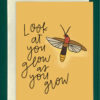 Close-up of a yellow greeting card on top of a cream-colored envelope, all on a forest background. The card features a drawing of a firefly on the right-hand side. To the left reads the words, "look at you glow as you grow"