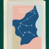 Close-up of a white greeting card on top of a cream-colored envelope, all on a forest background. The card features the constellation Aquarius superimposed on abstract blobs of different colors - dark blues, pinks, and beige. Text at the top of the greeting card reads, "Happy Birthday to my favorite Aquarius"