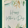 Close-up product image of a greeting card in front of a cream envelope. The card features drawings of sprays of gold and green leaves that frame the top and the bottom of the card. In the center reads, "Happy Mother's Day" in a large script.